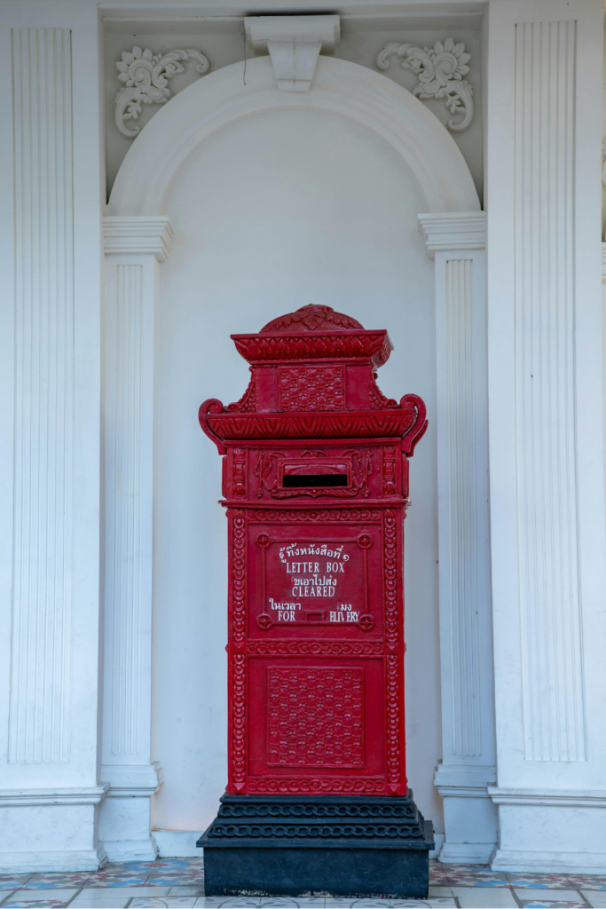 白い背景の前に立つ赤い郵便ポスト